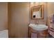 Powder room featuring a wood vanity, white sink, and a wood-framed mirror with warm lighting at 10390 Hondah Dr, Littleton, CO 80127