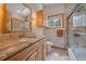 This bathroom is complete with a wood vanity, granite countertops, tiled floors, and a shower with a glass door at 10390 Hondah Dr, Littleton, CO 80127