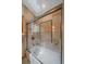 A beautifully tiled shower featuring a sliding glass door is accented by a skylight and vanity lighting at 10390 Hondah Dr, Littleton, CO 80127