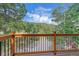 Enjoy this mountain home's beautiful wood deck with black metal railing overlooking a lush landscape and scenic views at 10390 Hondah Dr, Littleton, CO 80127