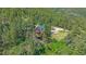 Aerial view of a charming two-story cabin nestled among lush trees with a green metal roof at 10390 Hondah Dr, Littleton, CO 80127