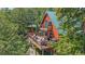 Aerial view of a charming cabin with a wrap-around deck, nestled among lush trees at 10390 Hondah Dr, Littleton, CO 80127
