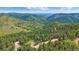 Wide scenic aerial view of a mountain cabin surrounded by rolling hills, trees, and mountains at 10390 Hondah Dr, Littleton, CO 80127