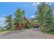 Charming cabin exterior featuring wood siding, stone foundation, and a gravel driveway at 10390 Hondah Dr, Littleton, CO 80127
