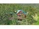 Aerial view of a charming cabin with a green roof, with a wrap-around deck, nestled among lush trees at 10390 Hondah Dr, Littleton, CO 80127