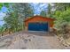 Single-car garage with wood siding and a blue garage door is located in a wooded area at 10390 Hondah Dr, Littleton, CO 80127