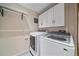 Efficient laundry room with white cabinets and modern appliances including front loading washer and dryer at 10390 Hondah Dr, Littleton, CO 80127