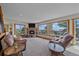 Cozy living room with stone fireplace and large windows showcasing scenic views and comfortable brown furniture at 10390 Hondah Dr, Littleton, CO 80127