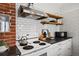 Updated kitchen featuring open shelves, stainless appliances, and brick accent wall at 9551 W 38Th Ave, Wheat Ridge, CO 80033