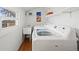 Bright laundry room with a washer, dryer, utility sink, hardwood floors, a window, and open shelving for storage at 9551 W 38Th Ave, Wheat Ridge, CO 80033