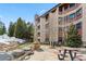 Beautiful exterior of the building with a stone grill, patio, and nearby evergreens and snow at 405 Village Rd # 405, Breckenridge, CO 80424