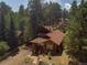 Aerial view of the house with a wood roof surrounded by tall pine trees in a tranquil neighborhood at 29090 Golf Way, Evergreen, CO 80439