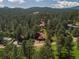 Stunning aerial view of a home nestled among the trees with a mountain backdrop at 29090 Golf Way, Evergreen, CO 80439