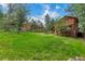 Expansive backyard featuring mature trees, a wooden fence, and a view of the home at 29090 Golf Way, Evergreen, CO 80439