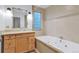 Bathroom featuring a tiled bathtub, vanity, and unique stone-trimmed mirror at 29090 Golf Way, Evergreen, CO 80439