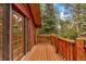 Wood deck with rustic railings and glass door showcasing the beautiful wooded scenery at 29090 Golf Way, Evergreen, CO 80439