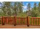 Outdoor deck with wooden railing overlooking a lush, green forest and mountain views at 29090 Golf Way, Evergreen, CO 80439