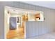 Open concept living room leading to kitchen, featuring a pass-through window and wood-paneled walls at 29090 Golf Way, Evergreen, CO 80439