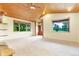Bright living room featuring large windows with views of the lush, green outdoors and wood-paneled ceilings at 29090 Golf Way, Evergreen, CO 80439