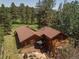 Back of home with a wood deck, patio and fire pit, nestled next to a golf course and trees at 29090 Golf Way, Evergreen, CO 80439