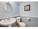 Charming powder room with blue walls, pedestal sink, and decorative mirror, offering a cozy and stylish space at 6708 S Niagara Ct, Centennial, CO 80112