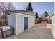 Shed with gray wood siding, a blue door, and a concrete pad, perfect for storage and a workspace at 6708 S Niagara Ct, Centennial, CO 80112
