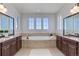 Luxurious bathroom featuring double sinks, a soaking tub, and elegant neutral tile work at 8727 Hunters Hill Ln, Littleton, CO 80125