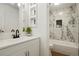 Well-lit bathroom featuring a stylish vanity and updated tub with marble-style tile surround at 3047 W 47Th Ave # 607, Denver, CO 80211