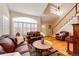 Bright living room features hardwood floors, a staircase, a large window, and leather furniture at 6454 S Nelson Way, Littleton, CO 80127