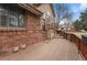 A backyard deck on a brick home with a wood railing and steps leading down to the yard at 7288 S Sundown Cir, Littleton, CO 80120
