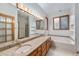 Bright bathroom with dual vanities, a soaking tub, tile floors, and wood framed windows at 7288 S Sundown Cir, Littleton, CO 80120