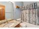 Bathroom featuring a granite countertop, framed mirror, and shower with pastel floral curtains at 7288 S Sundown Cir, Littleton, CO 80120