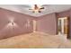 Spacious bedroom with carpeted floors, ceiling fan, light sconces, and two entry doors at 7288 S Sundown Cir, Littleton, CO 80120