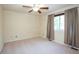 A neutral carpeted bedroom featuring a ceiling fan and natural light from a window with neutral-toned curtains at 16873 Boreas Ct, Parker, CO 80134