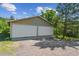 Two-car detached garage featuring white doors surrounded by greenery and a driveway at 5073 N Lariat Dr, Castle Rock, CO 80108