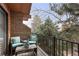View of a private balcony with cushioned chairs and a table, surrounded by mature trees at 16052 Deer Ridge Dr # B, Morrison, CO 80465