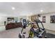 Basement area with exercise equipment, comfortable brown sofa, fireplace, and large screen television at 16052 Deer Ridge Dr # B, Morrison, CO 80465