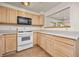 Kitchen with wooden cabinetry, microwave, range and view into other room, offering convenience and style at 6868 Johnson St, Arvada, CO 80004
