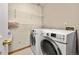 Well-equipped laundry room with white washer and dryer, wire shelving, and tile floor at 6868 Johnson St, Arvada, CO 80004
