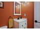 Bright bathroom featuring a white vanity with sink, matte black faucet, updated fixtures, and vibrant orange walls at 48 Galapago St, Denver, CO 80223