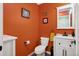 Charming bathroom with a toilet, vanity, mirror and decorative art pieces adorning the vibrant orange walls at 48 Galapago St, Denver, CO 80223