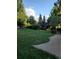 Lush backyard featuring a well-maintained lawn, mature trees, and a concrete walking path at 7290 S Cook Cir, Centennial, CO 80122