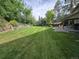 Sprawling backyard with lush, green lawn, mature trees, and a wooden retaining wall, offering privacy at 7290 S Cook Cir, Centennial, CO 80122