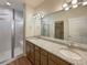 Bathroom featuring dual sinks, granite countertops, and a glass-enclosed shower at 120 Sabin Way, Lochbuie, CO 80603