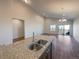 A modern kitchen island features a double sink and granite counters, flowing into the living space at 120 Sabin Way, Lochbuie, CO 80603