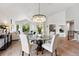 Elegant dining room showcasing a round glass table and a modern chandelier with hardwood flooring at 1361 Castlepoint Cir, Castle Pines, CO 80108