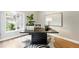 Bright home office featuring a large black desk, light hardwood floors, and a zebra hide rug at 1361 Castlepoint Cir, Castle Pines, CO 80108