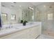 Modern bathroom featuring double sink vanity, marble counters, and glass-enclosed shower with herringbone tiling at 535 N High St, Denver, CO 80218