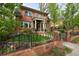 Charming two-story red brick home featuring a welcoming front porch and manicured front yard with wrought iron fence at 535 N High St, Denver, CO 80218