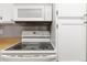 Close-up of a clean, white stove top, microwave and cabinetry, adding a modern touch to the kitchen at 1847 S Union Blvd, Lakewood, CO 80228